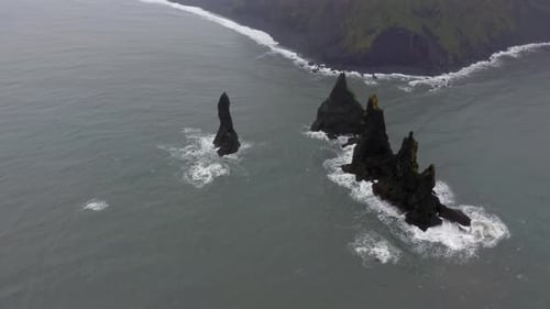 Aerial: Drone crane shot of Reynisdrangar sea stacks in Reynishjara black sand beach in Iceland