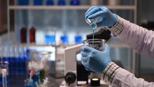 Scientist pours blue liquid in lab, close-up