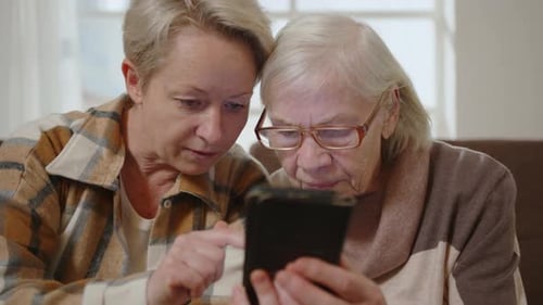 Two Women Using Smartphone Together Indoors