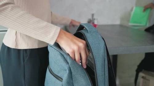 Woman Packing Backpack with Water and Lunch