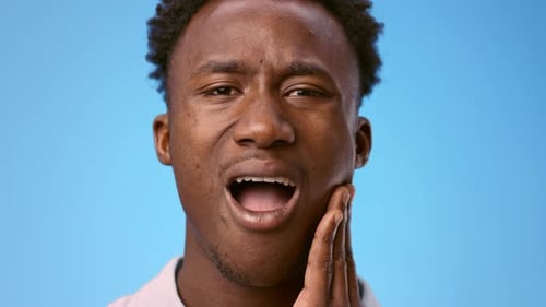 Sick Young Black Man Poses Against a Bright Blue Background