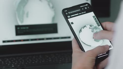 Adult Using Phone with Cyberthreat Map