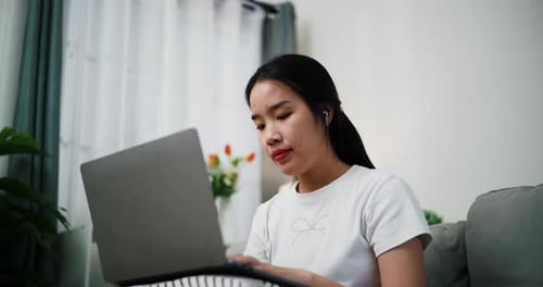 Young Woman Working Thoughtfully at Home on Laptop