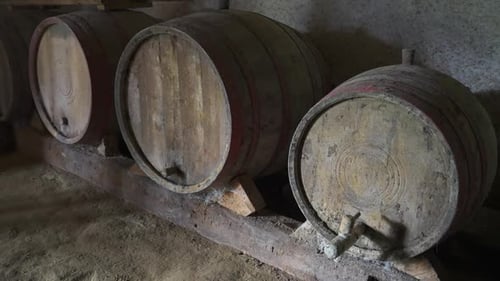 Close-up of old wooden wine barrels inside a dimly lit rustic cellar