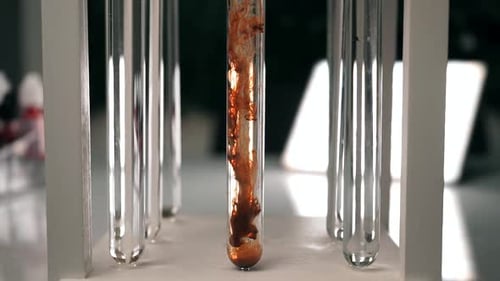 El reactivo químico marrón se disuelve lentamente en un tubo de ensayo con un líquido transparente.