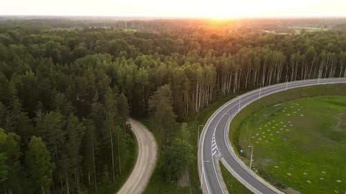 Captivating Aerial View of a Forested Landscape with a Curved Road Bathed in the Warm Glow of the