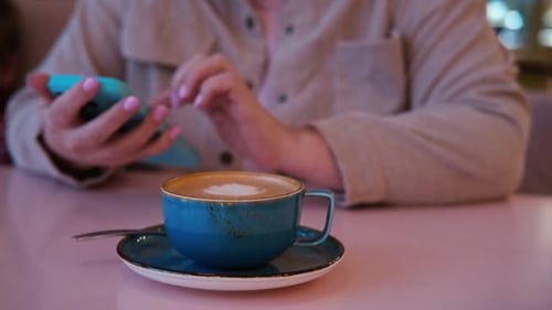 Unerkennbare Frau benutzt Handy und trinkt Kaffee in einem Café beim Surfen in sozialen Medien weiblich