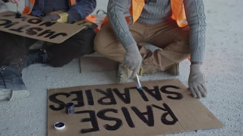 People Painting Labor Protest Signs on the Ground