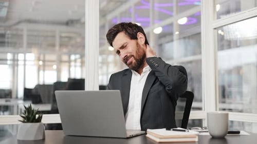 Businessman with Neck Pain From Stressful Office Work on Laptop