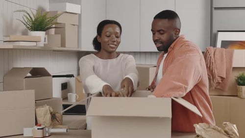 Couple Packing Moving Boxes Together Inside Home