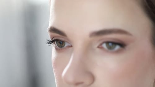 Visagist trägt Mascara auf das Gesicht einer Frau im Haus auf, Nahaufnahme