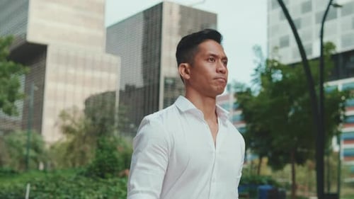 Young businessman is walking on modern building background