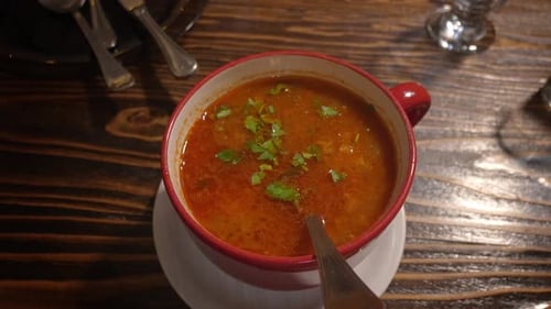 Steaming red soup in a cozy restaurant setting with a vibrant mug