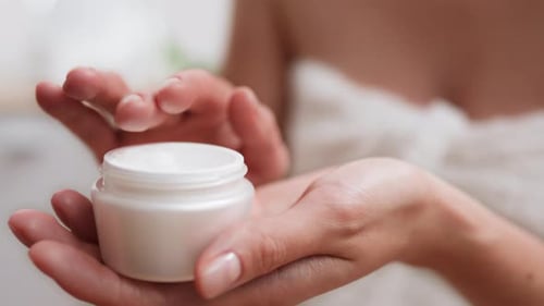 Woman Applies Cream to Hands in a Bright Room