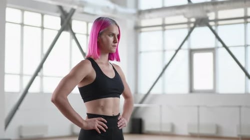 Fit Woman with Pink Hair Stands in Bright Gym