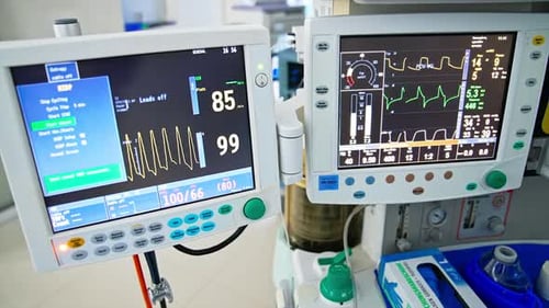 Two screens in the operating room showing different parameters during surgery.