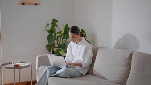 Woman Using Laptop Computer on Couch at Home