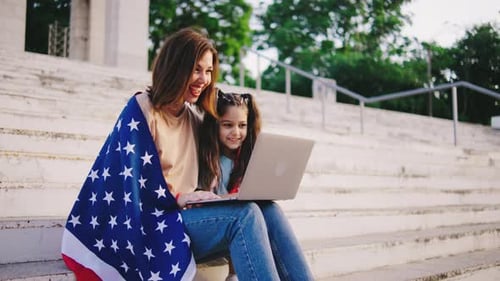 Woman and Girl Using Laptop With American Flag