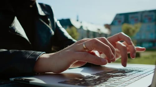 Hands Typing on Laptop in City Environment