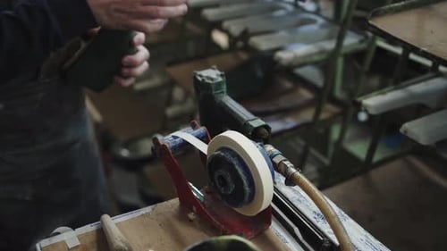 Craftsman buffs sole of a sandal on in workshop