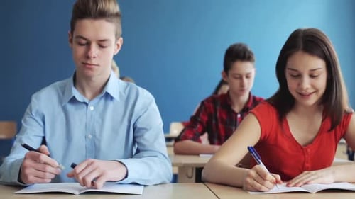 Happy students take notes and study together in a bright school classroom