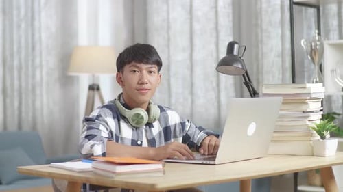 Teenager lernen online vom Laptop und lächeln zu Hause zur Kamera