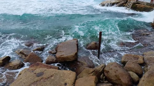 Slow-motion shot of water crashing against rocks, showcasing the power of the ocean and the dramatic