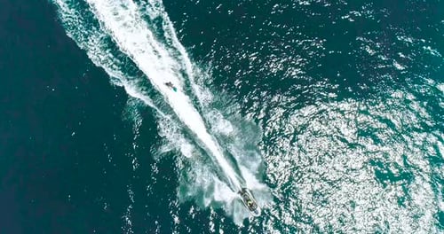 Jetski- und Surffahrer auf Jetski in der tropischen blauen und grünen Meereswasserlandschaft. Luftfuß von oben nach unten