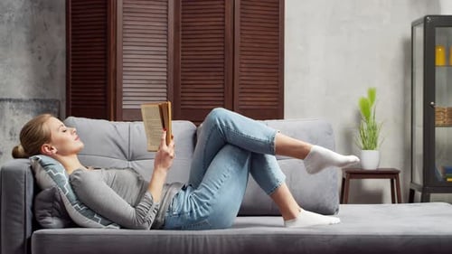 Woman Lying on Couch Reading a Book