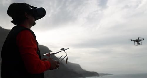 Man Wearing VR Headset Flying Drone Near Coast