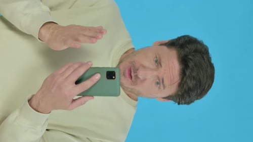 Verlust eines jungen Mannes auf dem Smartphone auf blauem Hintergrund, vertikales Video