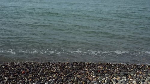 Sea waves rush onto the pebble beach, calm weather at sea, seascape for relaxation, reflection