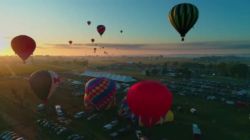 Aerial view of multiple hot air balloons early morning take off into the sun during a festival on a