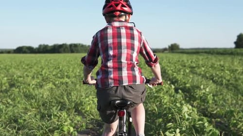A Boy in a Helmet Rides a Mountain Bike in the Park
