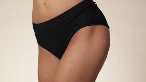 Primer plano de la cadera de una mujer irreconocible en ropa interior. Grabado con una cámara de helio RED en 8K.