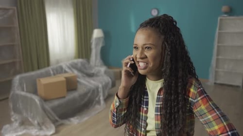 Portrait of an African American Woman in the Living Room Talking on the Phone The Woman Swears on
