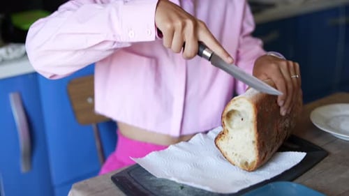 Young Adult Cuts Bread Loaf in Kitchen