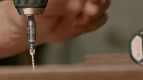 Close up of a man carpenter using screwdriver while working with a wooden product