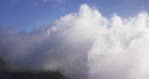 Drone view of high white clouds moving over the Haleakala volcano on Maui, Hawaii at daylight.