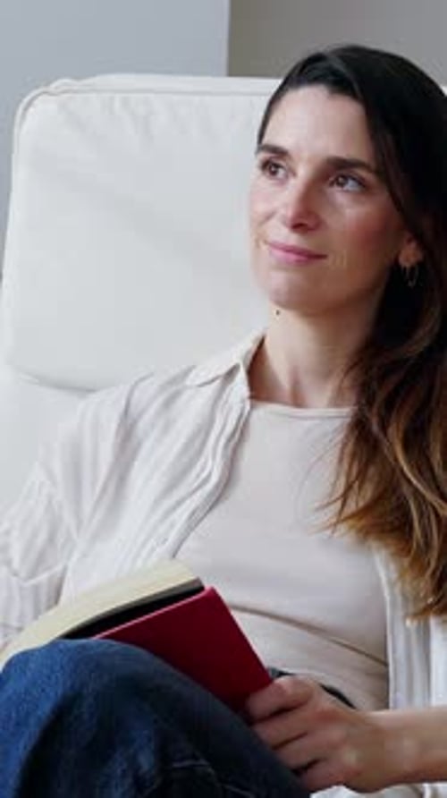 Mid Adult Woman Reading a Book in a White Chair