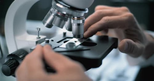 Close Up of Microbiologist Putting Fossil Specimen Under Microscope