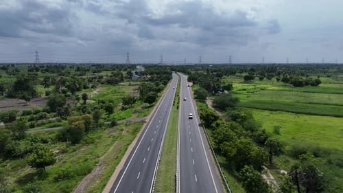 Expansive highway cutting through the Indian countryside, surrounded by lush greenery