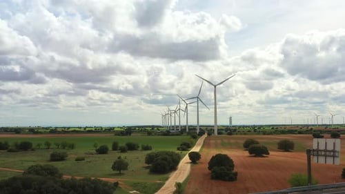 Aerial Drone View of Wind Turbines Across Rural Farmland with Cloudy Bright Sky
