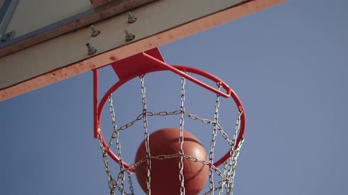 Orange Basketball Ball Hits Hoop Against Blue Sky Background Closeup