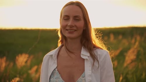 Young Woman Smiling in Rural Field at Sunset