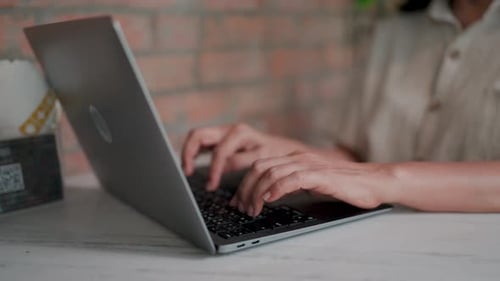 Close-up shot showcases hands skillfully typing on a sleek laptop, revealing a dedication