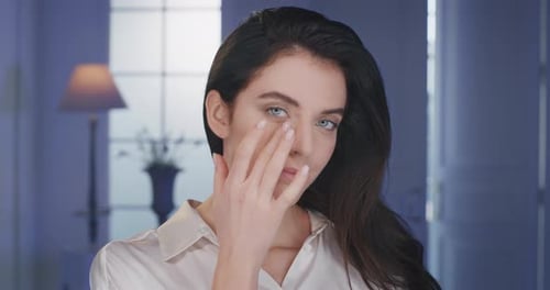 Beauty shot of mature woman with perfect face skin after applying moisturizing cream is touching w