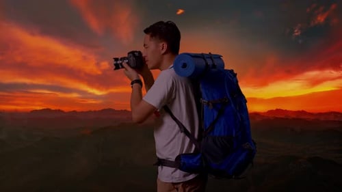 Seitenansicht eines asiatischen Mannes mit einer Kamera beim Fotografieren auf dem Gipfel des Berges