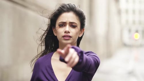 Young Woman Points Toward Camera in City
