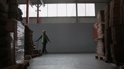 Fabrikarbeiter transportiert Kisten auf einem Wagen in einem geräumigen Lagerhaus